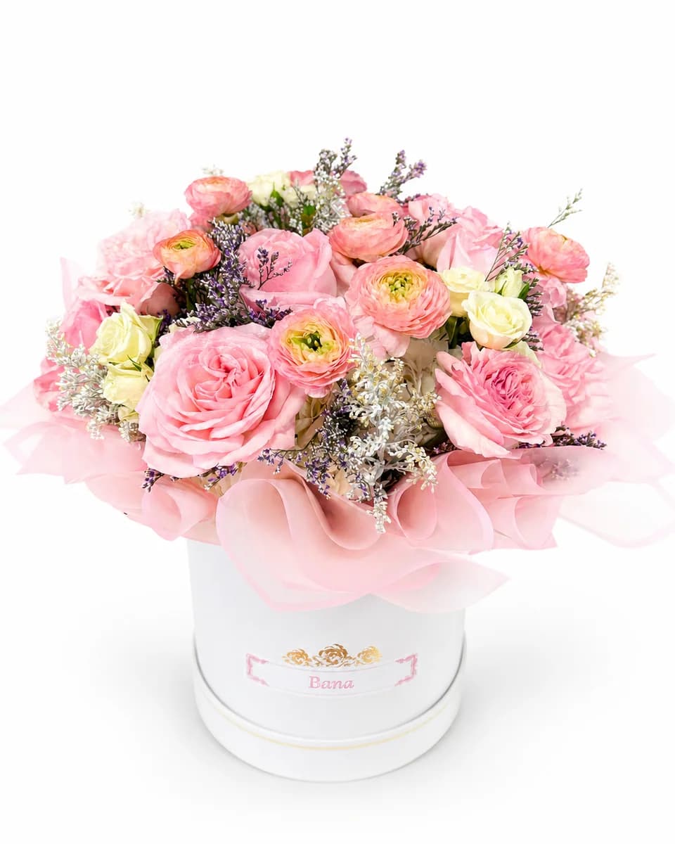 Pink garden roses and coral ranunculus in a white round box from Bana Florist Toronto